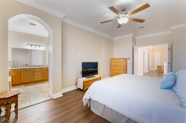 bedroom featuring light wood finished floors, visible vents, and crown molding