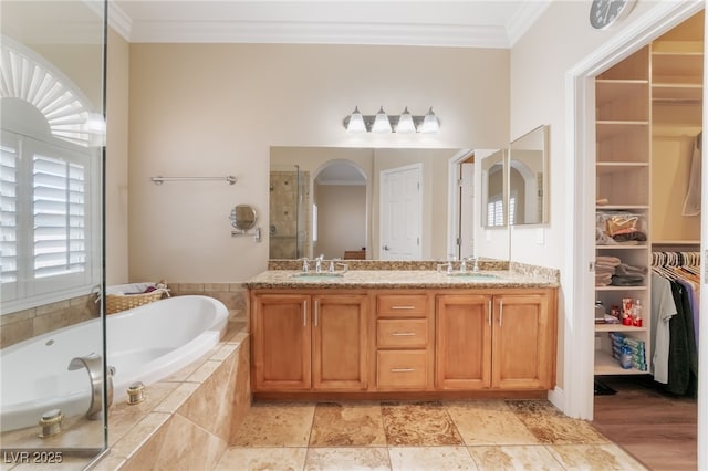 bathroom with ornamental molding, a bath, a stall shower, and a sink