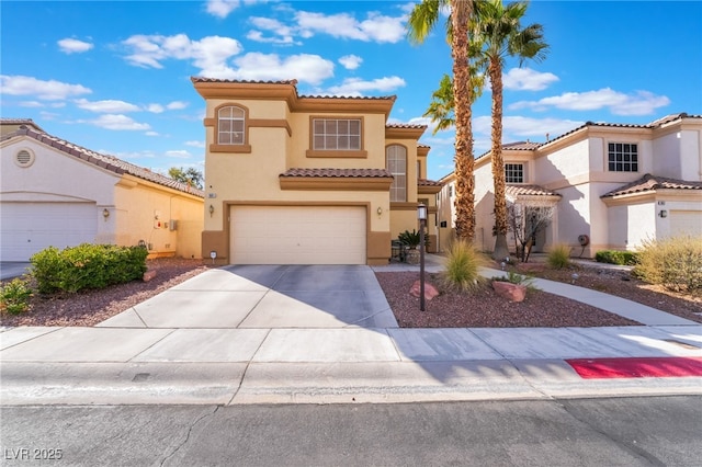 mediterranean / spanish-style house with concrete driveway, a tiled roof, a garage, and stucco siding