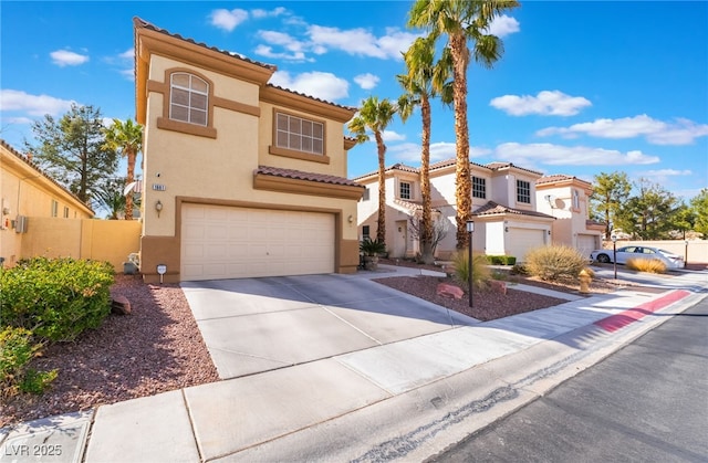 mediterranean / spanish-style home featuring fence, a residential view, stucco siding, driveway, and an attached garage