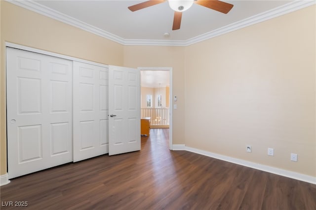 unfurnished bedroom with dark wood-style floors, baseboards, ceiling fan, ornamental molding, and a closet