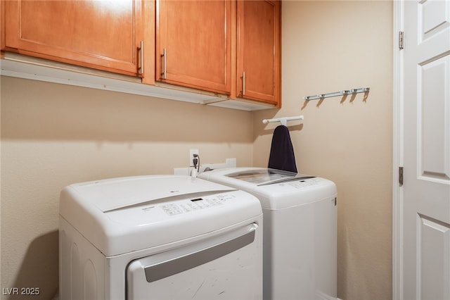 clothes washing area featuring cabinet space and independent washer and dryer