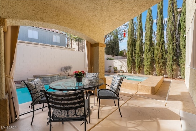 view of patio / terrace with an in ground hot tub, outdoor dining area, and a fenced backyard