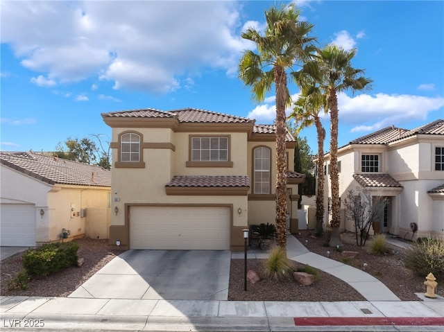 mediterranean / spanish home with concrete driveway, a tiled roof, a garage, and stucco siding