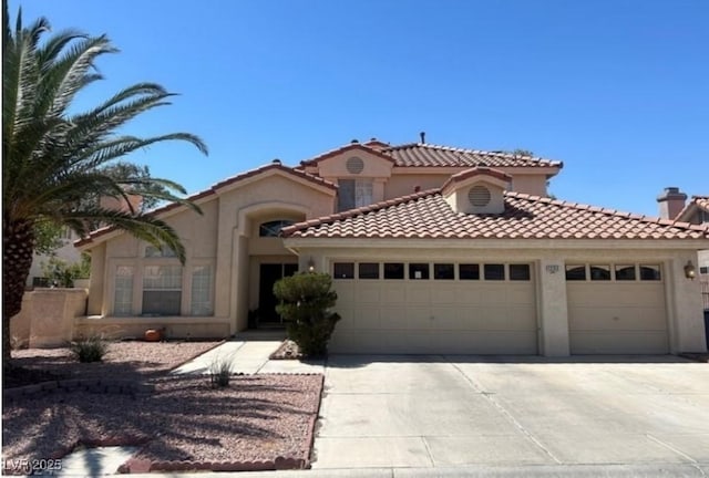 mediterranean / spanish-style house with a garage, stucco siding, driveway, and a tile roof