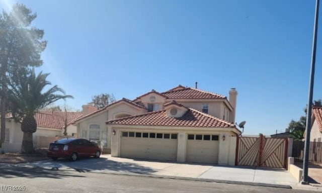 mediterranean / spanish-style house featuring a gate, a garage, fence, concrete driveway, and stucco siding