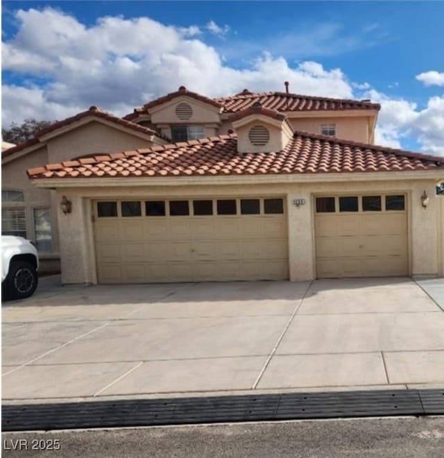 mediterranean / spanish-style house featuring a garage, stucco siding, concrete driveway, and a tile roof