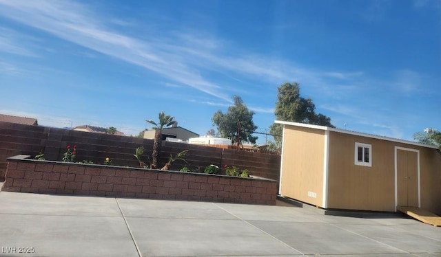 view of patio with fence, an outbuilding, and a storage unit