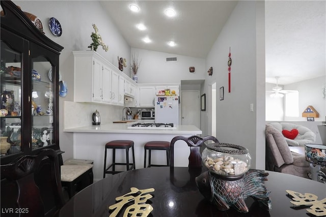 kitchen featuring ceiling fan, light countertops, vaulted ceiling, white appliances, and white cabinetry