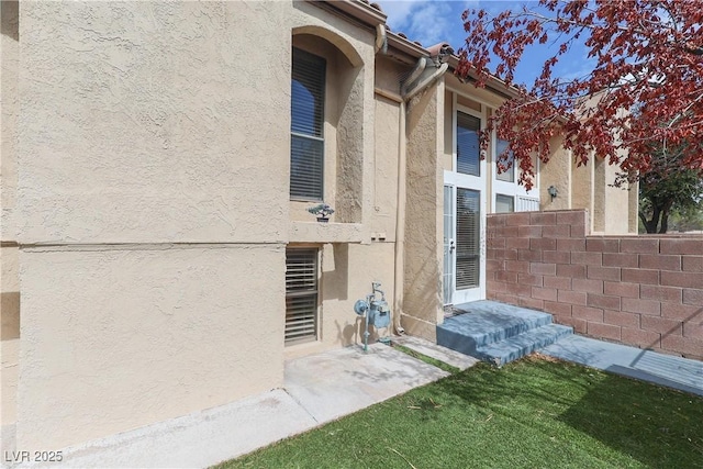 doorway to property featuring stucco siding and fence