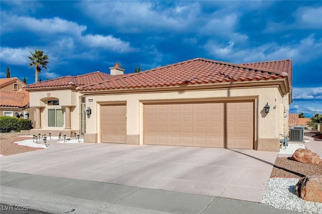 mediterranean / spanish home with central AC unit, driveway, an attached garage, stucco siding, and a tile roof