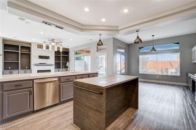 kitchen featuring gray cabinets, a sink, stainless steel dishwasher, open floor plan, and a center island