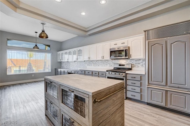 kitchen featuring light wood-style flooring, a kitchen island, tasteful backsplash, white cabinetry, and stainless steel appliances