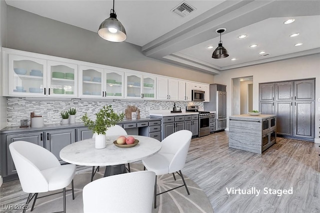 kitchen featuring visible vents, light wood-style flooring, white cabinets, appliances with stainless steel finishes, and backsplash