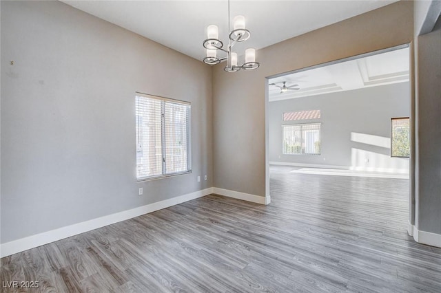 empty room with baseboards, wood finished floors, and ceiling fan with notable chandelier