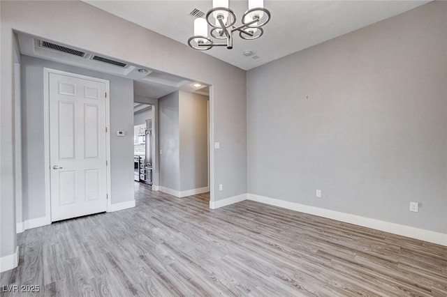 empty room with visible vents, baseboards, a notable chandelier, and light wood-style flooring