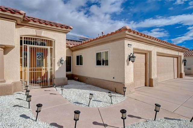 view of front facade with stucco siding, solar panels, concrete driveway, and an attached garage