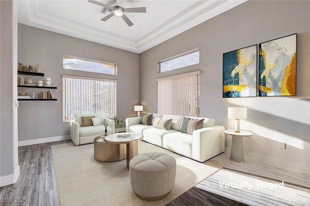 living area featuring wood finished floors, baseboards, a wealth of natural light, and ceiling fan