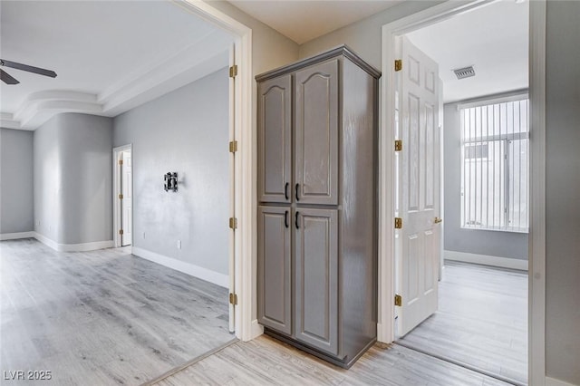 corridor featuring visible vents, baseboards, and light wood finished floors