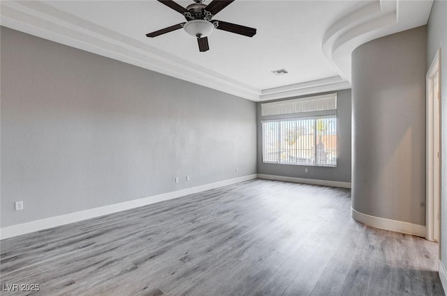 spare room with a ceiling fan, wood finished floors, baseboards, and visible vents