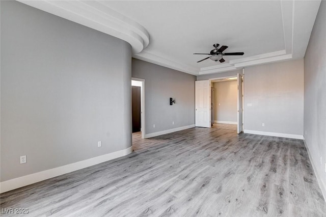 spare room featuring ceiling fan, baseboards, a tray ceiling, and wood finished floors