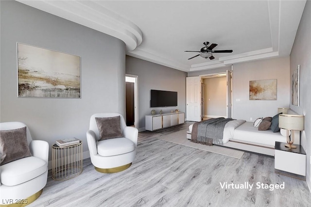 bedroom featuring a raised ceiling, wood finished floors, and ceiling fan