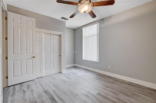 unfurnished bedroom with a ceiling fan, wood finished floors, visible vents, baseboards, and a closet