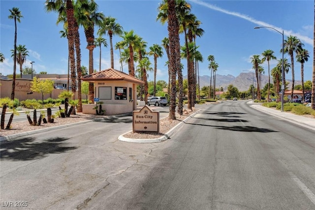 view of street featuring curbs, a mountain view, street lights, and sidewalks