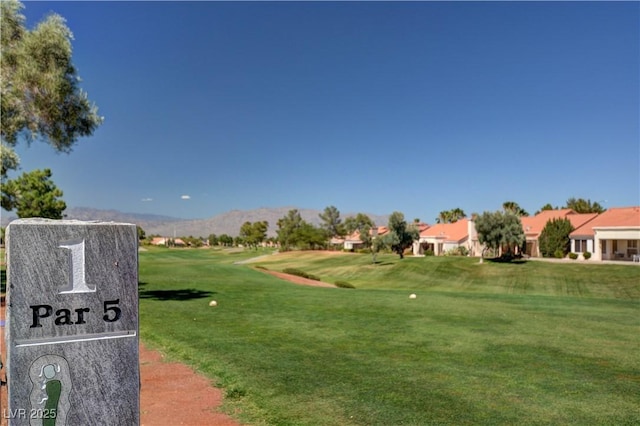 view of home's community with a mountain view, a yard, and view of golf course