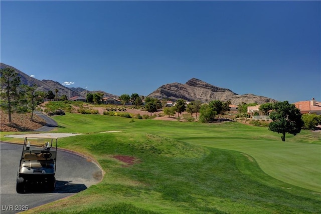 surrounding community with golf course view, a mountain view, and a yard