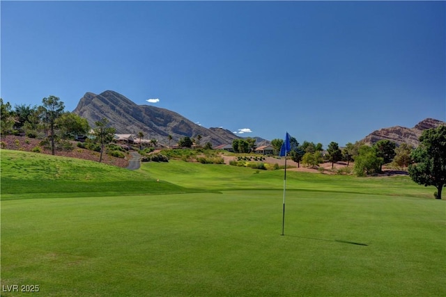 view of community featuring a mountain view, a lawn, and view of golf course