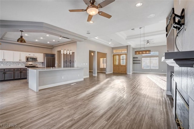 kitchen featuring ceiling fan, decorative backsplash, open floor plan, appliances with stainless steel finishes, and light wood-type flooring