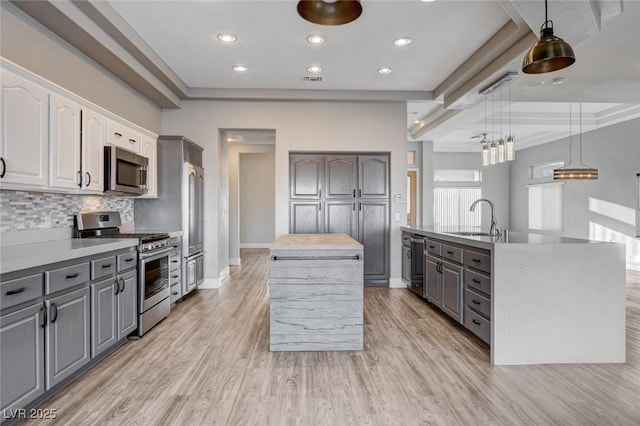 kitchen featuring a sink, gray cabinetry, stainless steel appliances, and a kitchen island with sink