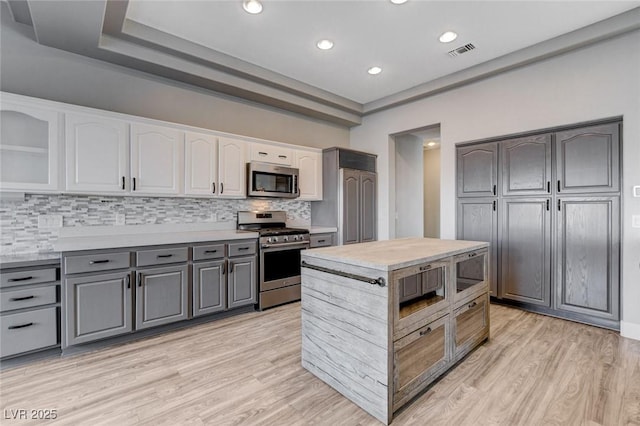 kitchen with visible vents, gray cabinets, stainless steel appliances, light countertops, and light wood-style floors