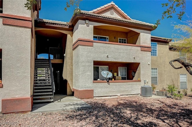 back of house with a tile roof, stairs, central AC, stucco siding, and a balcony