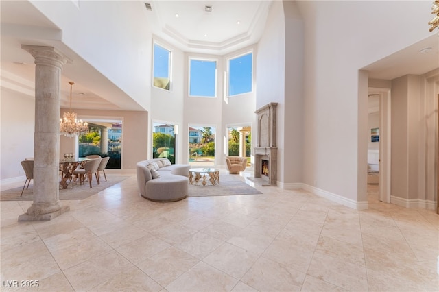 2221 Glenbrook Way, Las Vegas, NV 89117 - unfurnished living room featuring decorative columns, baseboards, a notable chandelier, and a warm lit fireplace