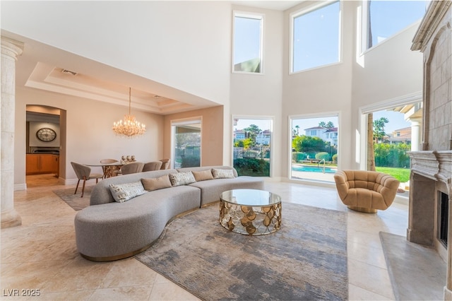 2221 Glenbrook Way, Las Vegas, NV 89117 - living area with light tile patterned floors, a premium fireplace, a tray ceiling, arched walkways, and a notable chandelier