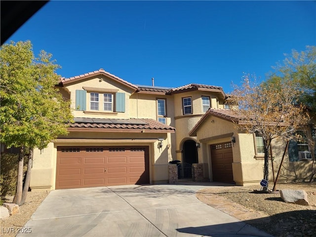 mediterranean / spanish-style house with a gate, stucco siding, concrete driveway, a garage, and a tiled roof