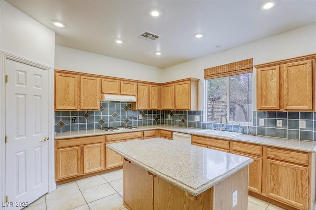 kitchen with visible vents, a kitchen island, light tile patterned flooring, a sink, and under cabinet range hood