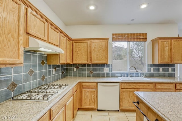 kitchen featuring white appliances, light tile patterned floors, a sink, light countertops, and under cabinet range hood