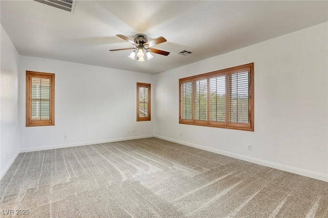 carpeted spare room featuring a ceiling fan, visible vents, and baseboards