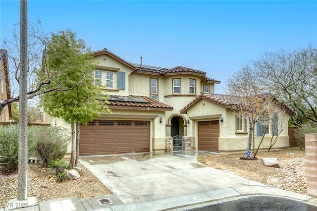 mediterranean / spanish home with stucco siding, concrete driveway, an attached garage, solar panels, and a tiled roof