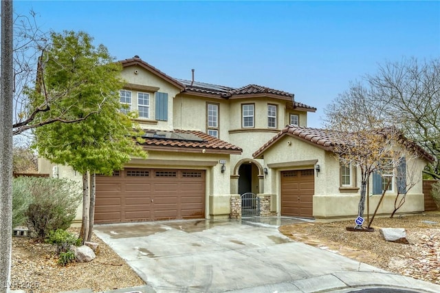 mediterranean / spanish-style home featuring stucco siding, concrete driveway, a garage, solar panels, and a tiled roof