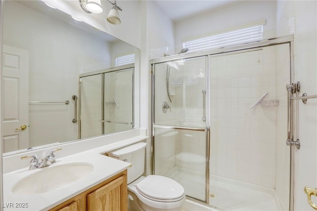 bathroom featuring a shower stall, toilet, and vanity
