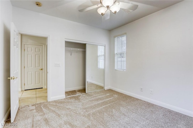 unfurnished bedroom with a closet, light colored carpet, baseboards, and ceiling fan