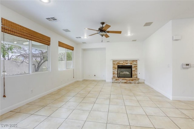 unfurnished living room featuring visible vents, a stone fireplace, light tile patterned floors, baseboards, and ceiling fan