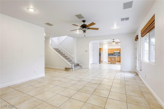 unfurnished living room featuring light tile patterned floors, visible vents, stairs, and a ceiling fan