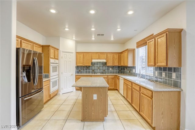kitchen with visible vents, a kitchen island, light tile patterned flooring, white appliances, and a sink