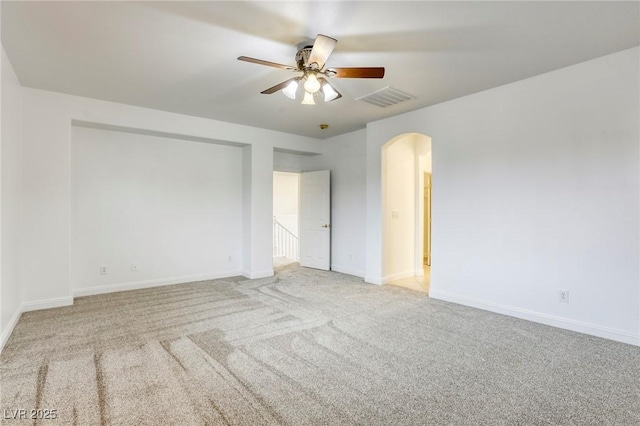 unfurnished room with a ceiling fan, visible vents, baseboards, arched walkways, and carpet flooring