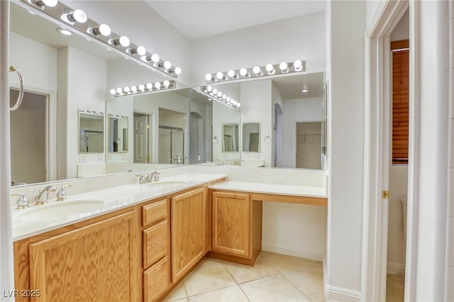 full bath with tile patterned floors, a shower with shower door, double vanity, and a sink